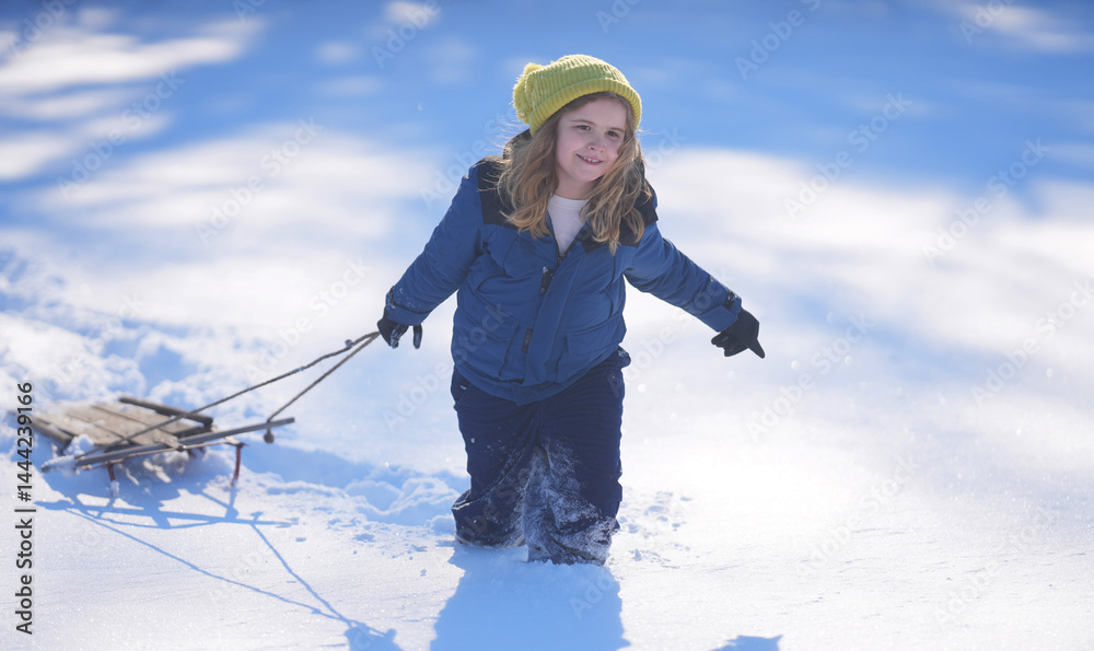 Kids Winter playing. Funny Kid play in the snow with a winter hat. Happy kid in warm clothes enjoying snow falling. Child play with snow outdoors during first snowfall. Winter activities for kids.