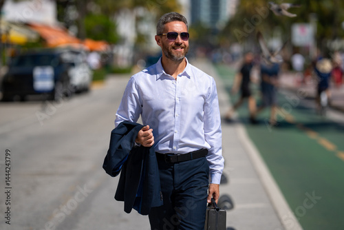 Obraz na płótnie Businessman walking confidently in the city. Businessman walking down the street. Handsome businessman walking on way to the office. Confident entrepreneur businessman walking outdoors. w salonie