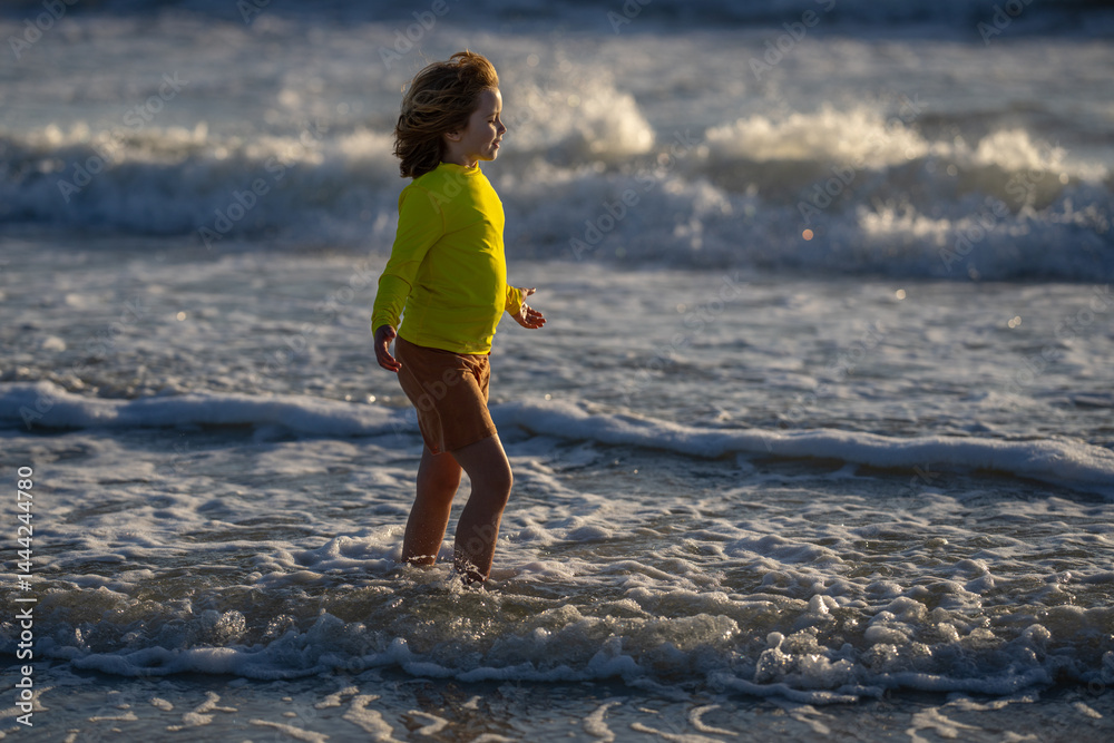 Carefree kid running on sea. Happy cute child running near ocean on warm summer day. A Cute little kid boy running and splashing in sea or ocean on a family vacation. Kid running along the beach.