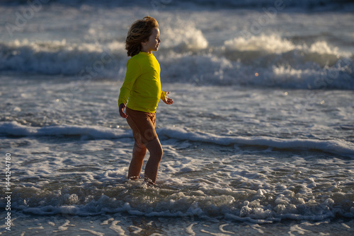 Obraz na płótnie Carefree kid running on sea. Happy cute child running near ocean on warm summer day. A Cute little kid boy running and splashing in sea or ocean on a family vacation. Kid running along the beach. w salonie