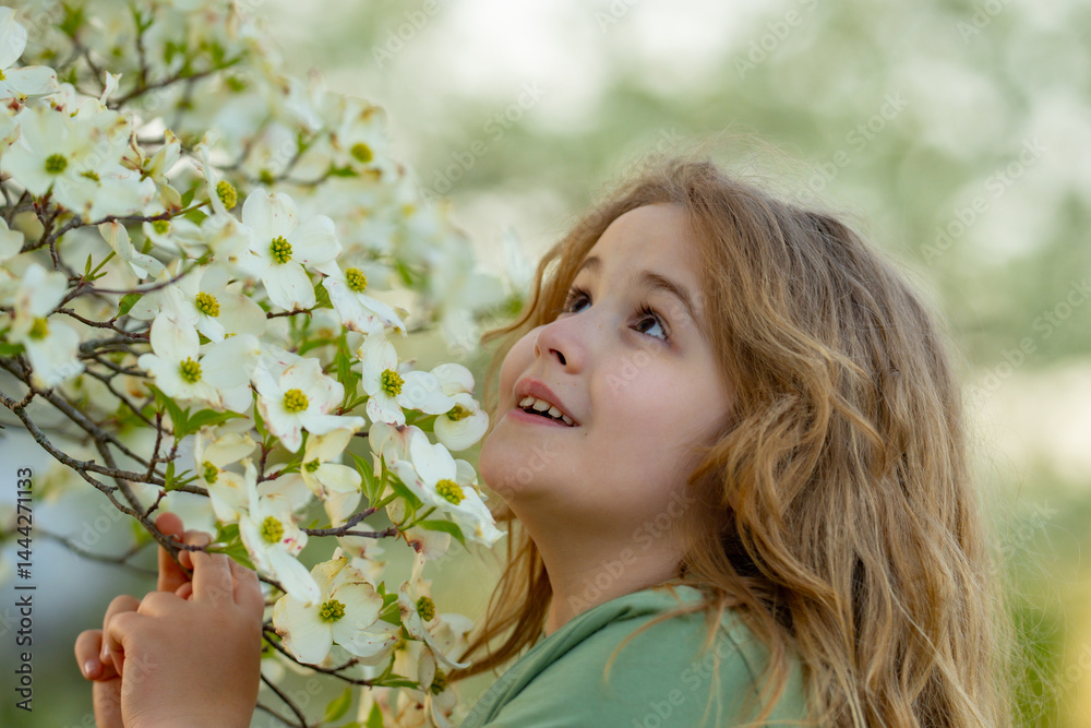 Spring flowers around child. Kid in blooming spring garden. Child face close to spring flowers. Dreamy kid portrait in spring orchard. Outdoors child portrait with blooming trees. Child and flowers.