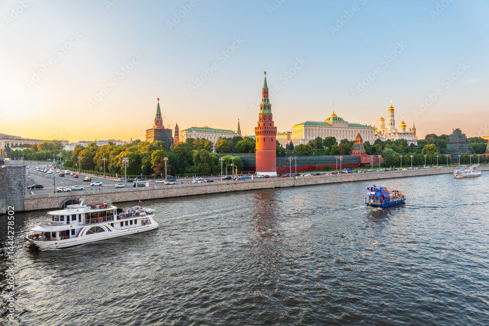 View of Kremlin with Vodovzvodnaya tower, Grand Kremlin Palace from repaired Bolshoy Kamenny Bridge in Moscow city on sunny summer day. Cruise ship sails on the Moscow river
