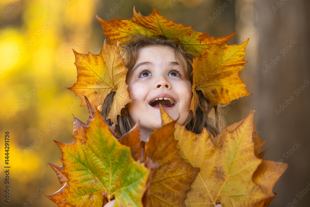 Autumn Child Face. Kid hold Fall Yellow Leaves. Little Child In Beautiful Autumn Park Outdoor. Kids play in autumn park. Child boy with oak maple leaf. Fall foliage. Kids face in autumn fall close up.