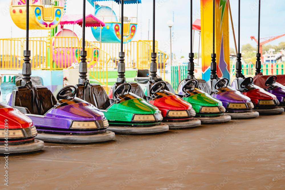 Colorful bumper cars are lined up at a vibrant amusement park, inviting thrilling excitement and joy at the amusement park
