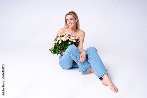 Obraz na płótnie A tender young woman in jeans and a shirt with flowers in the studio, natural beauty, lightness and romance for advertising and lifestyle content w salonie
