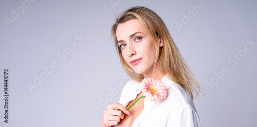 Obraz na płótnie Young woman with flower on light background, ideal for beauty, style and naturalness concepts w salonie