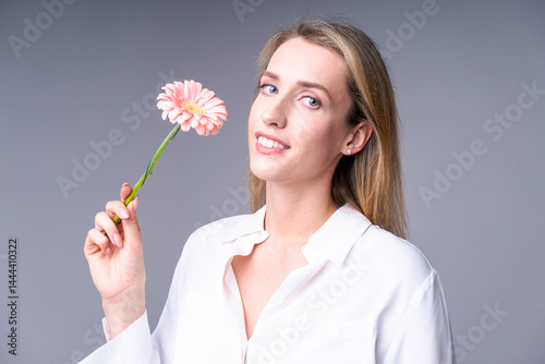 Obraz na płótnie Stylish woman with a flower on a light background, ideal for advertising fashionable clothes or accessories w salonie
