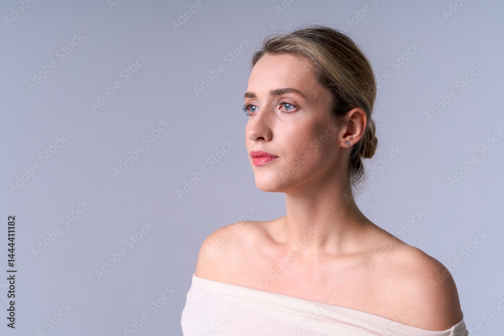 Young woman in beige top on light background, looking away. Ideal for beauty, style and self-care concepts
