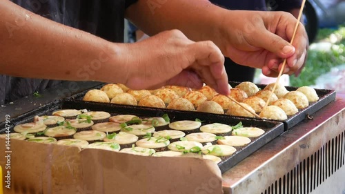 the process of cooking takoyaki using traditional molds, the most popular and delicious Japanese street food.