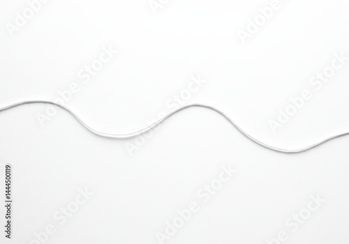 A single strand of grey thread undulating across a stark white background in a minimalist composition