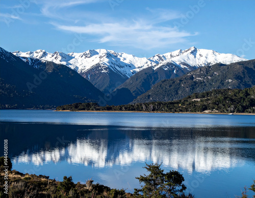 A scenic shot of the Andes mountains with snow-covered peaks reflecting on the calm waters of a serene lake. photo