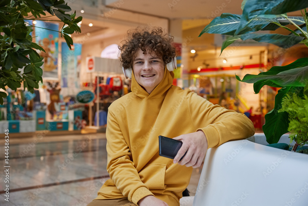 Teenage boy watching funny video on smartphone in shopping mall