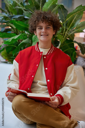 Obraz na płótnie Handsome teenage boy reading book while rest in shopping mall w salonie