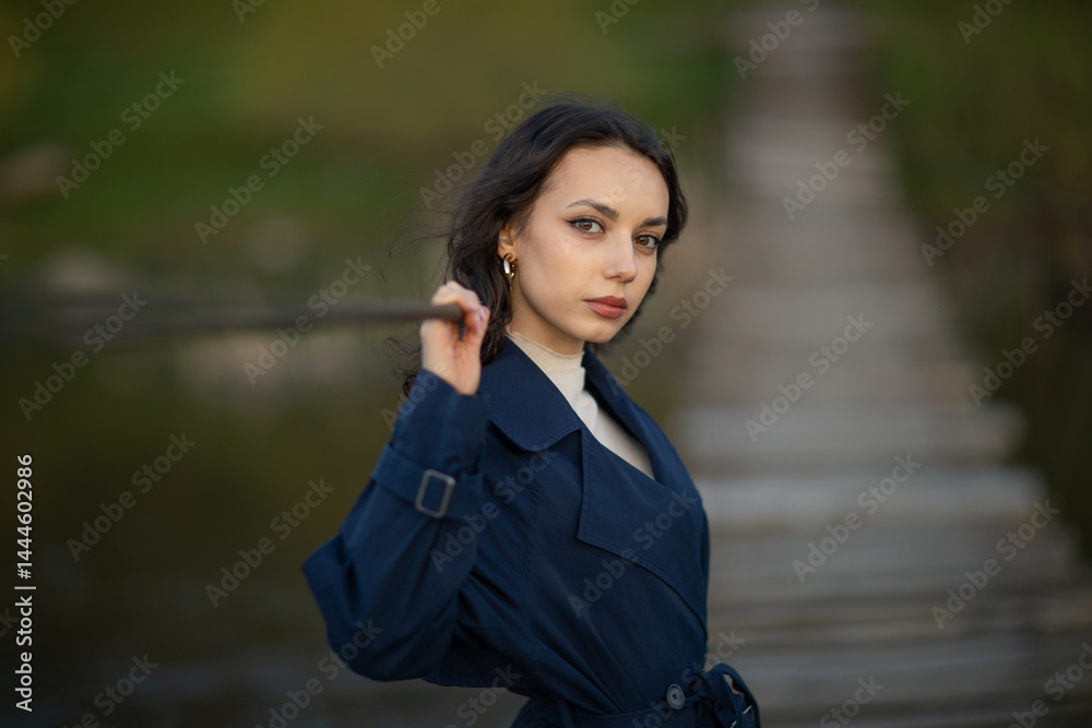 beautiful brunette european girl in blue trench coat at nature. Young lady with beautiful face.