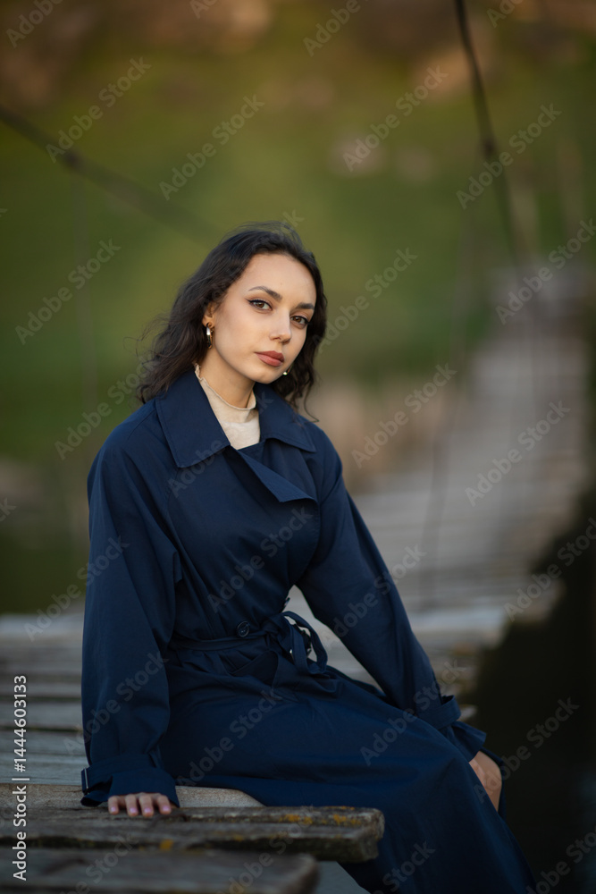 beautiful brunette european girl in blue trench coat at nature. Young lady with beautiful face.