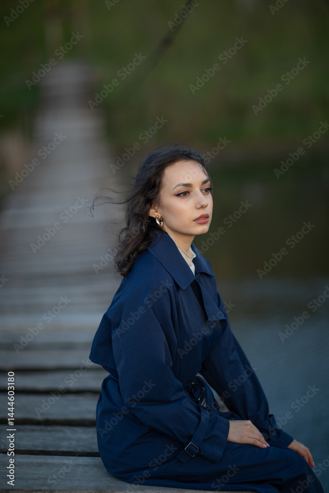 beautiful brunette european girl in blue trench coat at nature. Young lady with beautiful face.