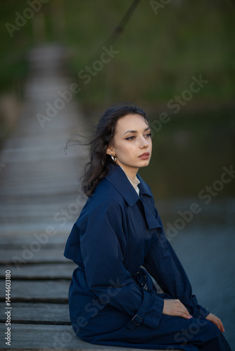 beautiful brunette european girl in blue trench coat at nature. Young lady with beautiful face.