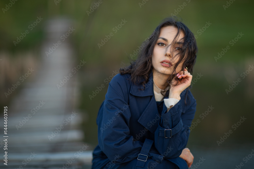 beautiful brunette european girl in blue trench coat at nature. Young lady with beautiful face.