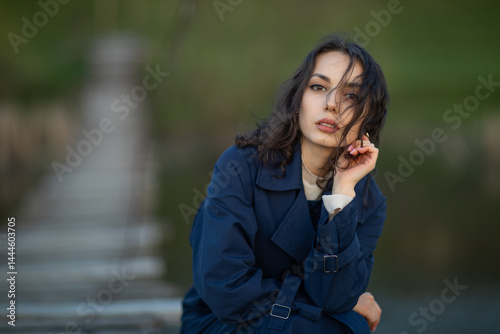 Obraz na płótnie beautiful brunette european girl in blue trench coat at nature. Young lady with beautiful face. w salonie