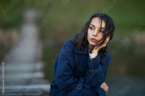 beautiful brunette european girl in blue trench coat at nature. Young lady with beautiful face.