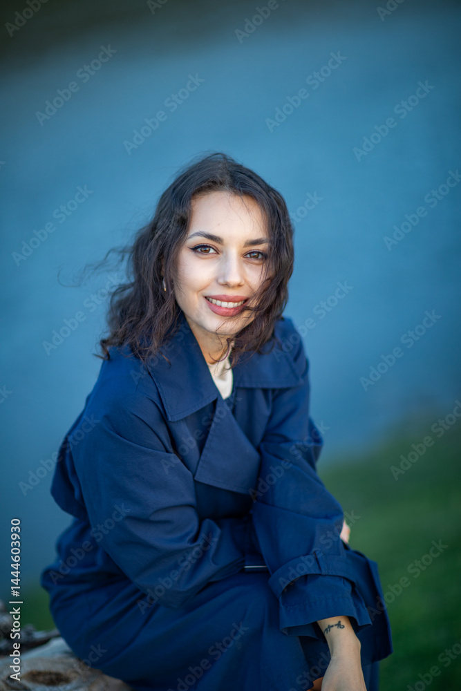 beautiful brunette european girl in blue trench coat at nature. Young lady with beautiful face.