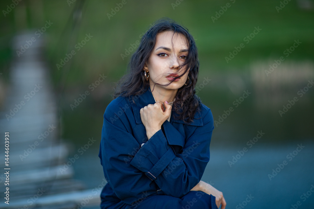 beautiful brunette european girl in blue trench coat at nature. Young lady with beautiful face.