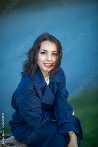 Obraz na płótnie beautiful brunette european girl in blue trench coat at nature. Young lady with beautiful face. w salonie