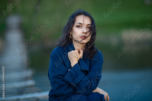 beautiful brunette european girl in blue trench coat at nature. Young lady with beautiful face.