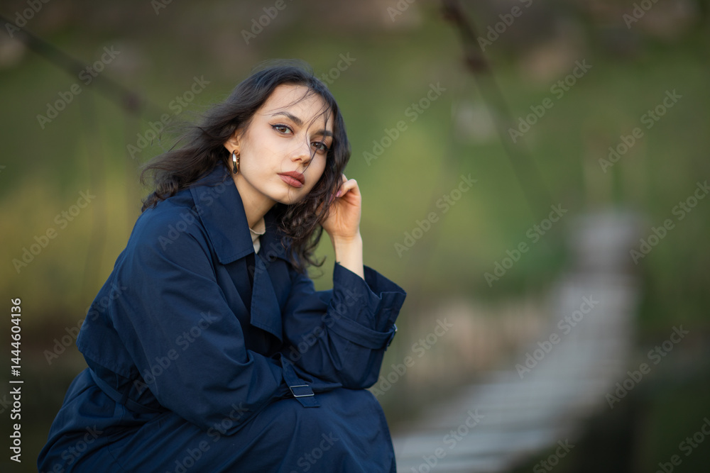 beautiful brunette european girl in blue trench coat at nature. Young lady with beautiful face.