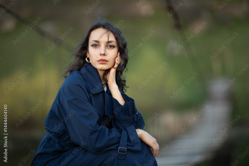 beautiful brunette european girl in blue trench coat at nature. Young lady with beautiful face.