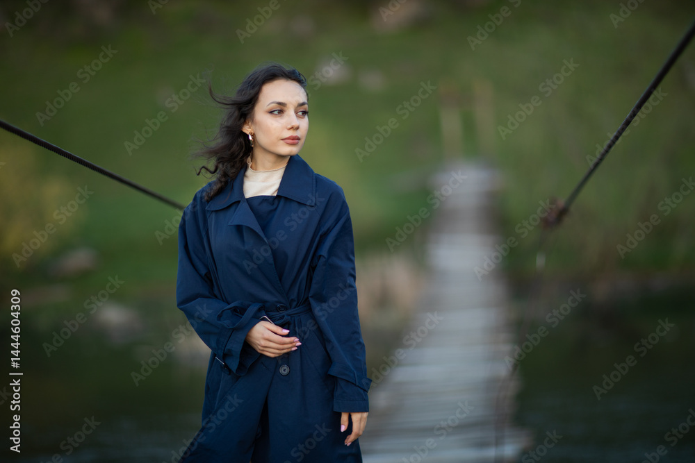 beautiful brunette european girl in blue trench coat at nature. Young lady with beautiful face.