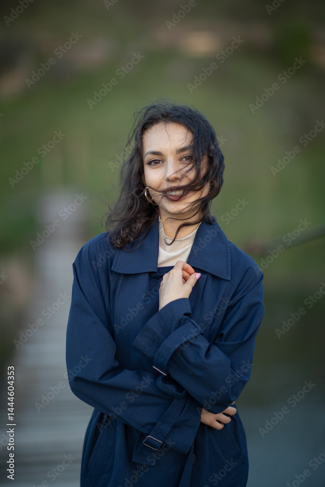 beautiful brunette european girl in blue trench coat at nature. Young lady with beautiful face.