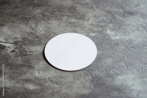 Blank circular coaster on textured gray surface, ideal for drink presentations and branding