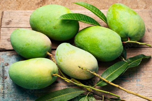 Green mango and green leaf on old wooden floor background, Group of raw mangoes organic with sour and high vitamin C fruit for healthy.