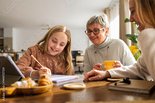Girl doing homework on a tabletwith mother and grandmother assising photo