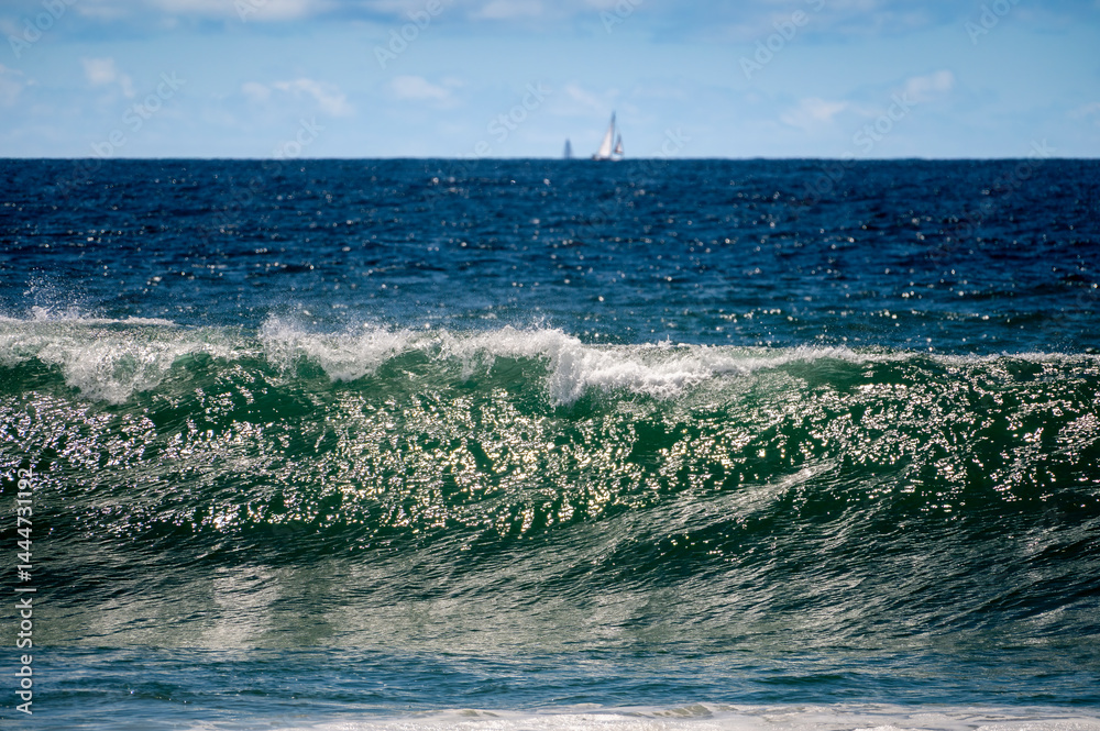 Wave forms giving a dramatic luster to the water with a boat in the background sitting on the horizon