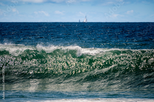 Obraz na płótnie Wave forms giving a dramatic luster to the water with a boat in the background sitting on the horizon w salonie