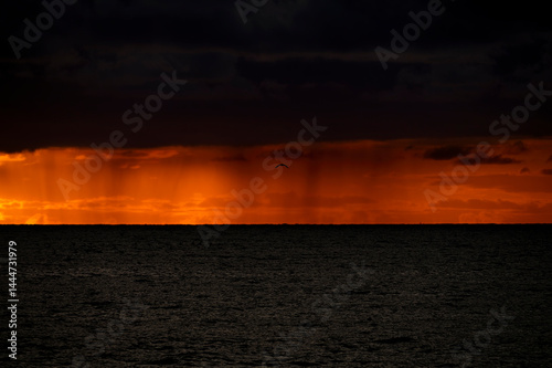 Obraz na płótnie Very moody and dramatic sky over the cloudy ocean horizon, with strong orange, sunbeams and traces of lingering storm cells w salonie