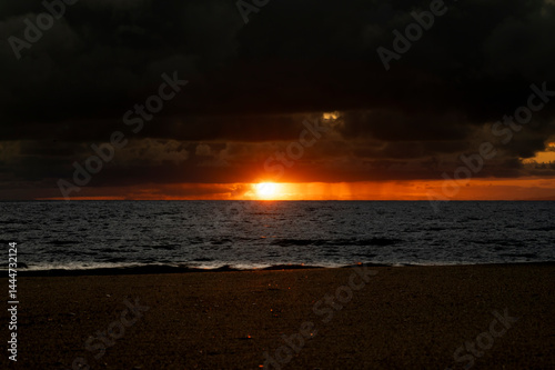 Obraz na płótnie Very moody and dramatic sky over the cloudy ocean horizon, with strong orange, sunbeams and traces of lingering storm cells w salonie