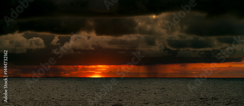Obraz na płótnie Very moody and dramatic sky over the cloudy ocean horizon, with strong orange, sunbeams and traces of lingering storm cells w salonie