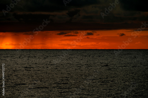 Obraz na płótnie Very moody and dramatic sky over the cloudy ocean horizon, with strong orange, sunbeams and traces of lingering storm cells w salonie
