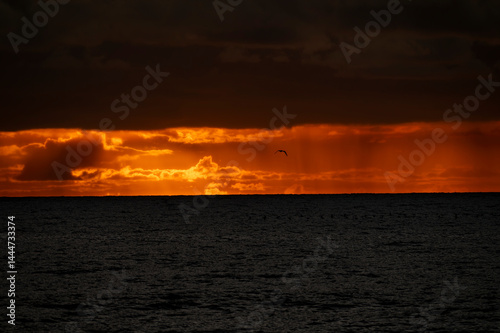 Obraz na płótnie Very moody and dramatic sky over the cloudy ocean horizon, with strong orange, sunbeams and traces of lingering storm cells w salonie