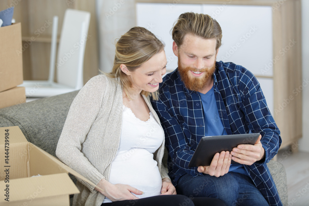 young couple sitting on sofa with tablet