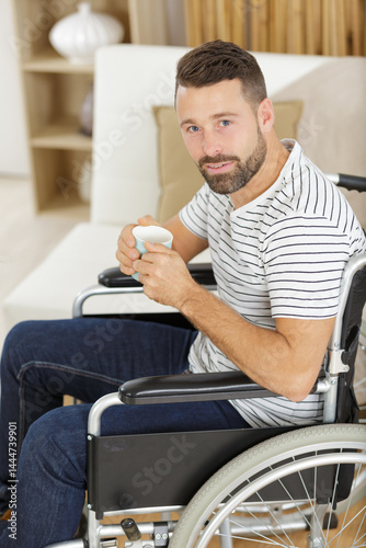 man in wheelchair drinking coffee indoors