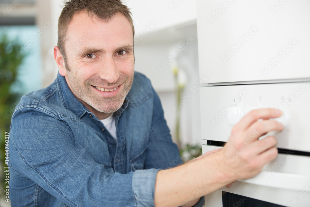 happy man using an oven in the kitchen