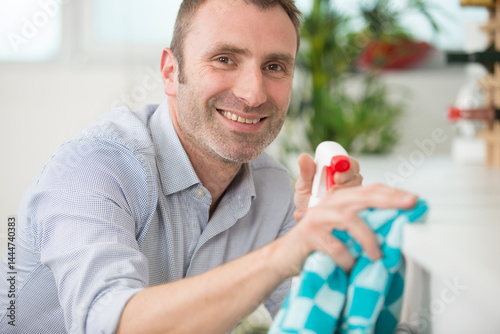 Obraz na płótnie man cleaning worktop with cloth and detergent spray w salonie