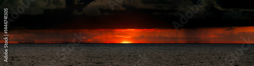 Obraz na płótnie Very moody and dramatic sky over the cloudy ocean horizon, with strong orange, sunbeams and traces of lingering storm cells w salonie