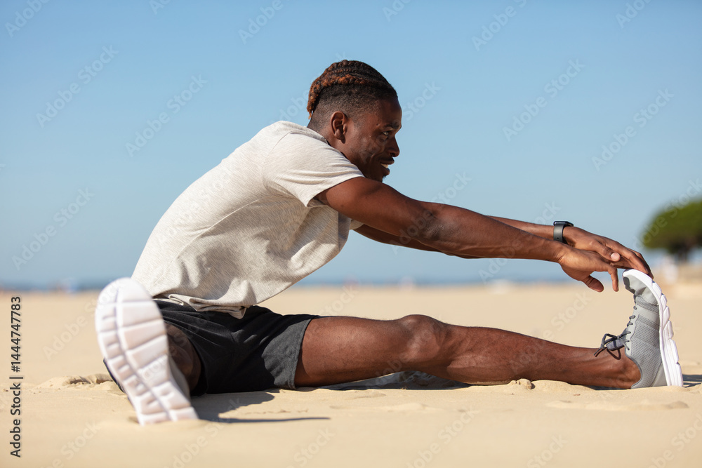 young african american man stretching on the beach