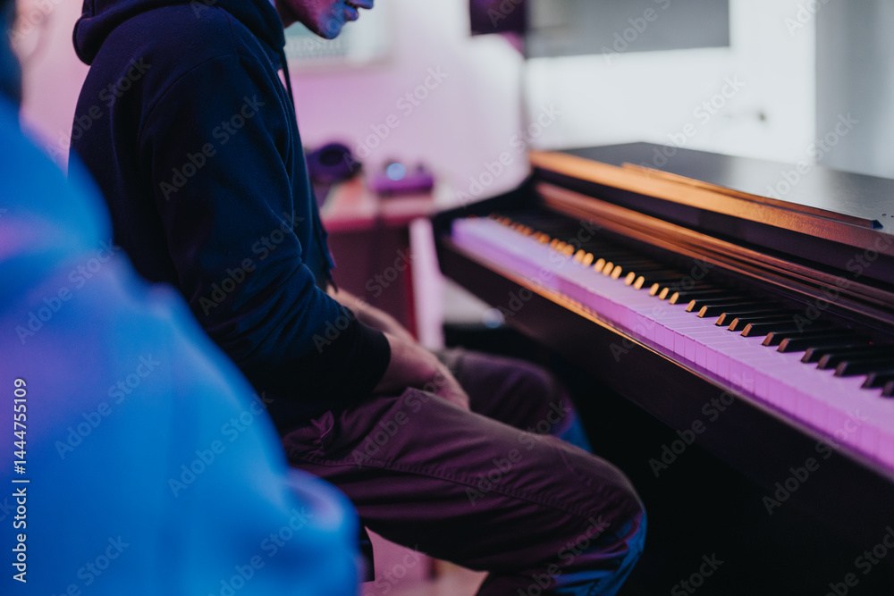 A musician immersed in music creation, playing the piano amidst colorful studio lighting. Capturing the essence of creativity, focus, and artistic expression in a modern music production setting.