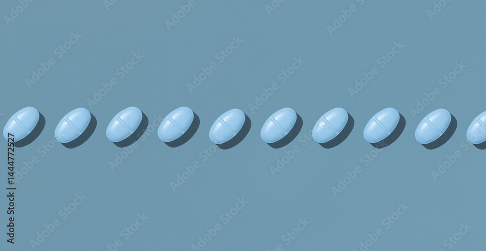 Blue medical pills in a line on blue top view, hard light. Pharmaceutical products for healthcare